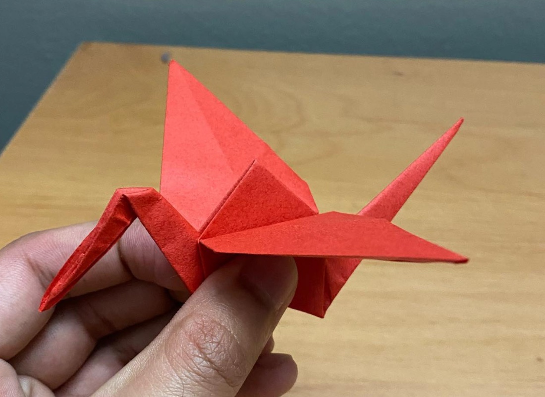 A red paper crane I folded, held in hand